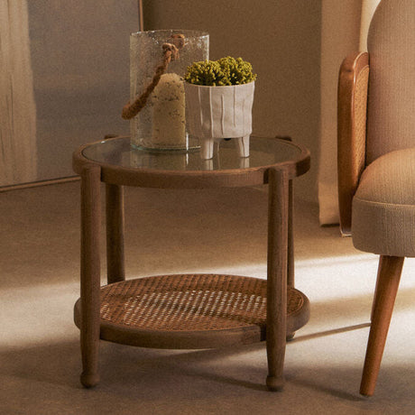 Orsina Side Table with a round glass top and a woven base, perfect for modern living rooms