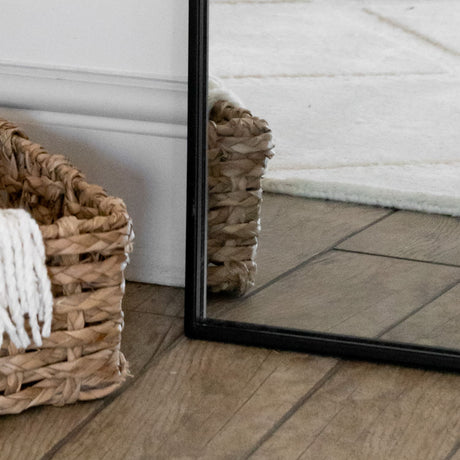 Jobu Home Arch Mirror with a sleek black frame reflecting a stylish woven basket