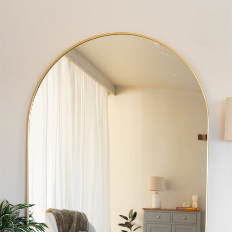 Elegant Arched Mirror with a gold frame, reflecting soft natural light in a modern home interior