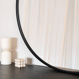 Stylish Circle Mirror by Jobu Home with a sleek black frame placed on a wooden surface
