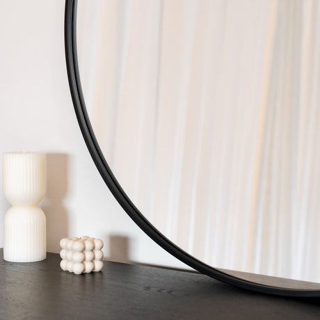 Stylish Circle Mirror by Jobu Home with a sleek black frame placed on a wooden surface