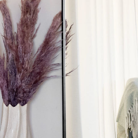 Stylish Jobu Home Oval Mirror with a sleek frame, reflecting modern decor and pampas grass arrangement