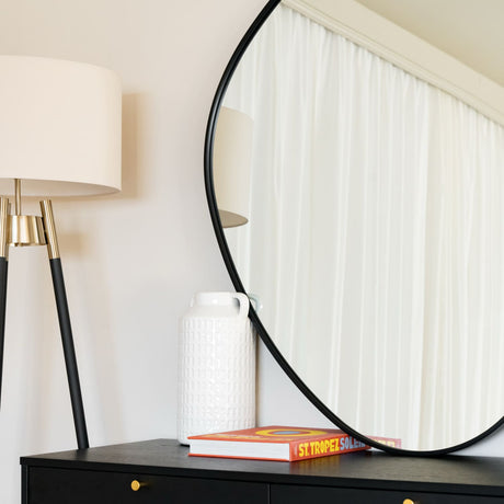 Jobu Home Pebble Mirror in round shape with stylish lamp and decor on a sleek black table
