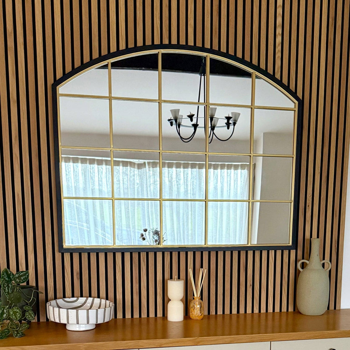 Jobu Home Window Mirror with an Arched Design and Gold Framed Grid on a Wooden Wall