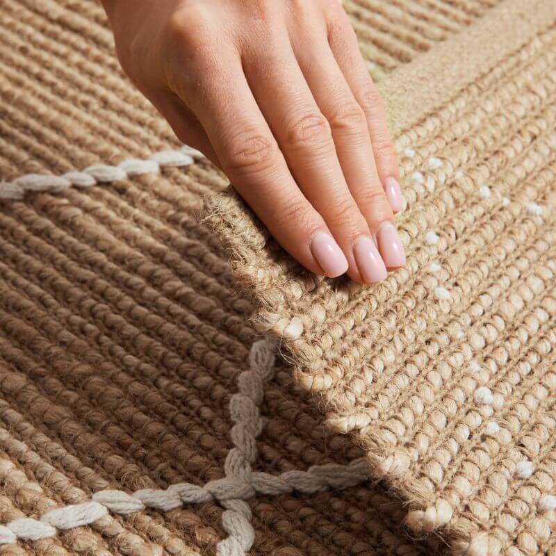 Hand showing the texture of a Jute Rug with intricately woven patterns and natural fibres