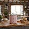 Orsina Pink Bread Bin with Silver Lid on a Wooden Kitchen Counter Alongside Freshly Baked Bread