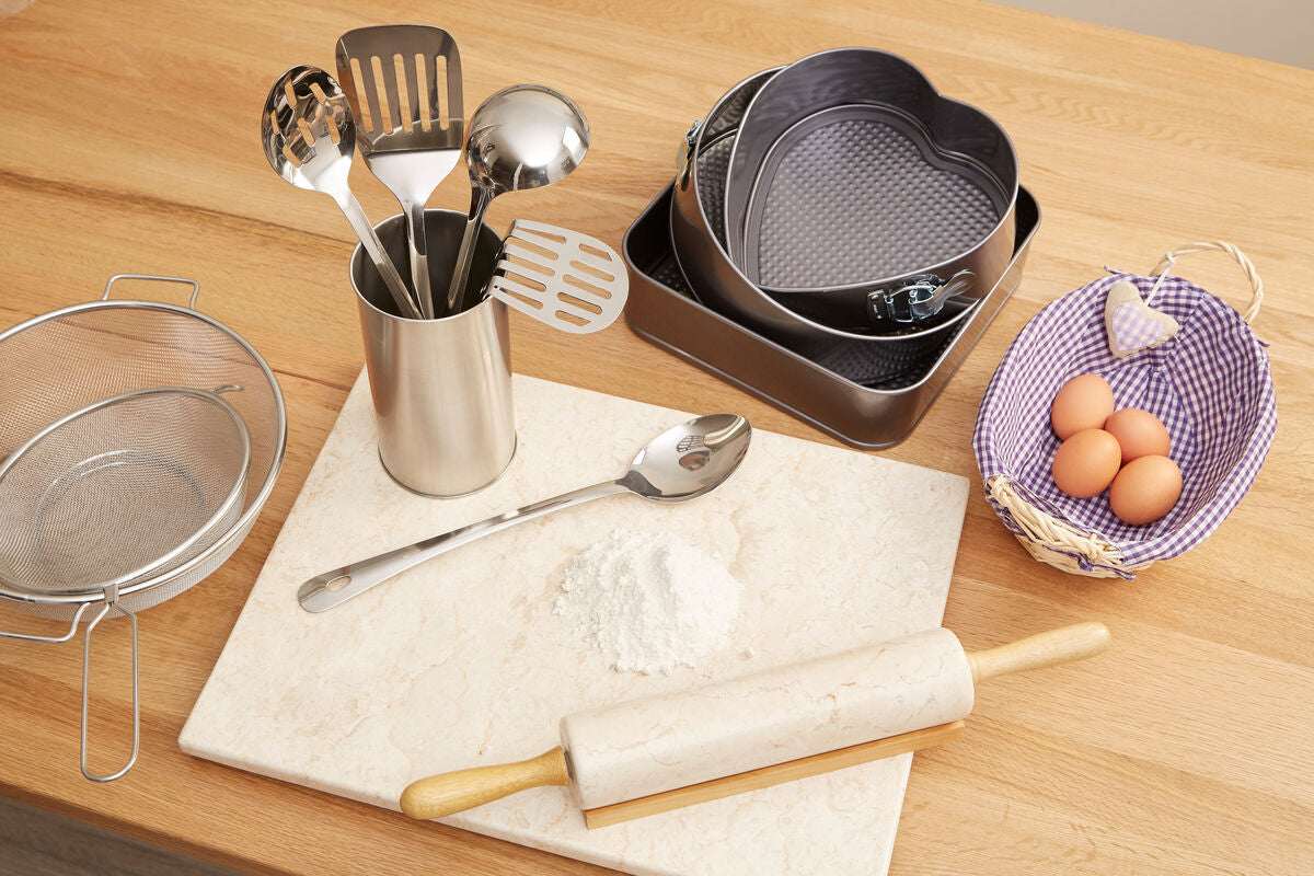 Assorted Orsina kitchen utensils including spatulas, measuring cups, and a rolling pin on a wooden countertop