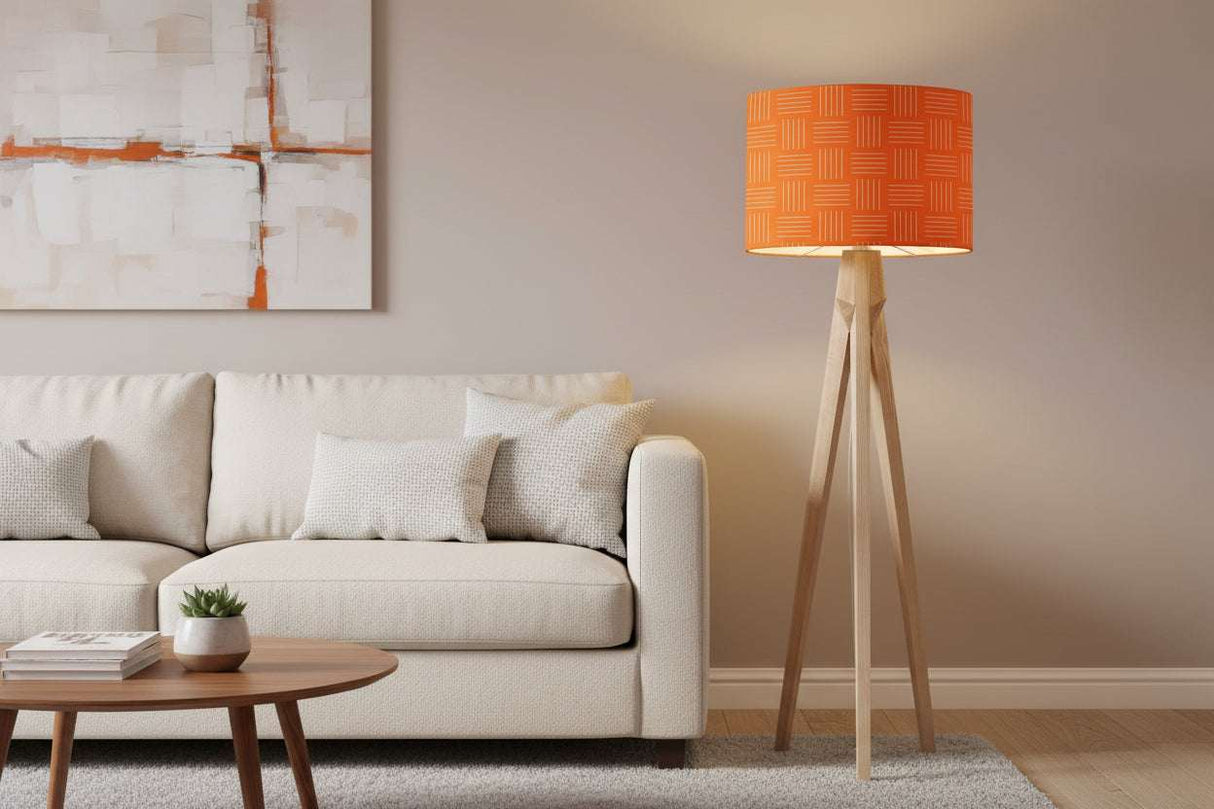 Orange patterned lampshade on a tripod floor lamp near a white sofa in a stylish living room