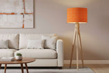 Orange patterned lampshade on a tripod floor lamp near a white sofa in a stylish living room