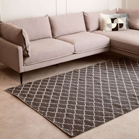 Orsina Lattice Rug in grey and white, placed under a stylish modern couch for a chic living room look
