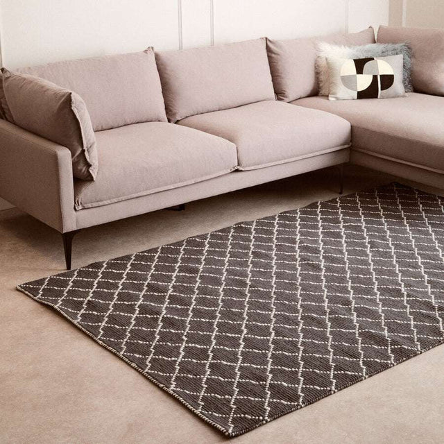 Orsina Lattice Rug in grey and white, placed under a stylish modern couch for a chic living room look