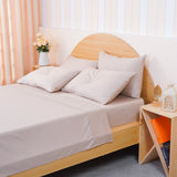 Soft beige fitted sheet on a bed with matching pillows in a stylish bedroom setting