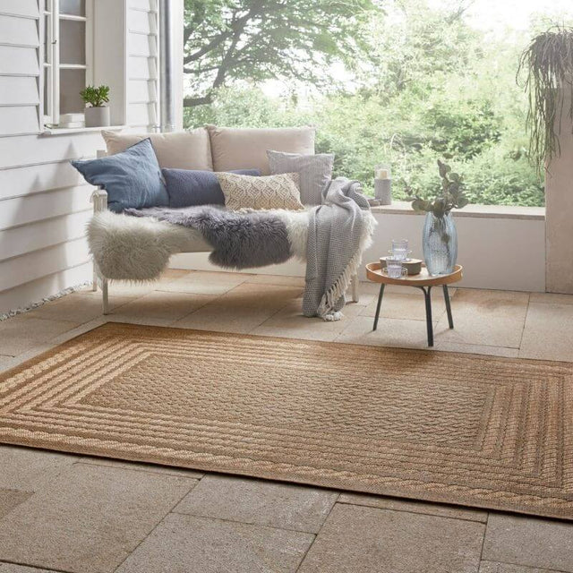 Limonero Rug in natural tones placed on a patio beside a stylish seating area