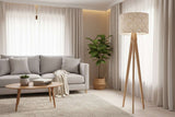 Stylish lampshade on a wooden tripod lamp in a modern living room with soft furnishings