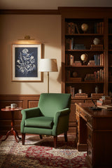 Elegant wall art featuring botanical prints in a cozy study with a green armchair and wooden desk