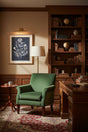 Elegant wall art featuring botanical prints in a cozy study with a green armchair and wooden desk