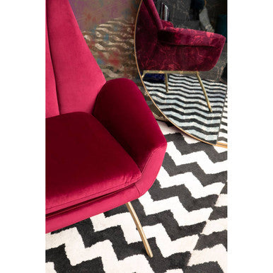 Stylish Orsina Lounge Chair in Burgundy Velvet with Gold Legs on a Zigzag Pattern Rug