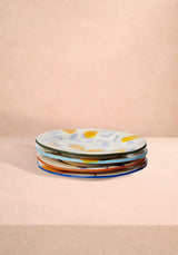Casa by Josephine Jenno Lunch Plates in Assorted Colours stacked on a beige surface