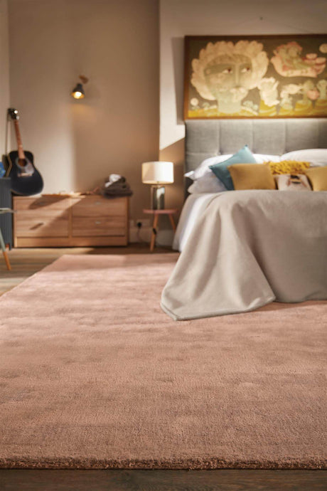 Luxury Rug in soft pink colour placed in a stylish bedroom with a wooden bed and decor