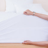 SHEET STORY Mattress Protector being fitted onto a mattress with a hand holding the fabric