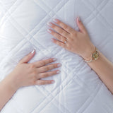 SHEET STORY Mattress Protector on a quilted mattress with hands resting atop for added comfort
