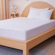 SHEET STORY Mattress Protector on a wooden bed frame, providing protection and comfort for a restful sleep