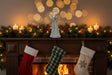 Metal Standing Angel decoration atop a festive mantel with lit candles and Christmas stockings