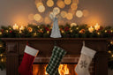 Metal Standing Angel decoration atop a festive mantel with lit candles and Christmas stockings