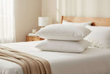 Two soft Microfibre Pillows stacked on a neatly made bed with a natural light setting