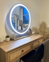 Modern round Hollywood mirror with LED lights above a stylish wooden vanity table