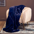 Orsina Navy Fur Throw draped over a cream armchair for a cozy living space