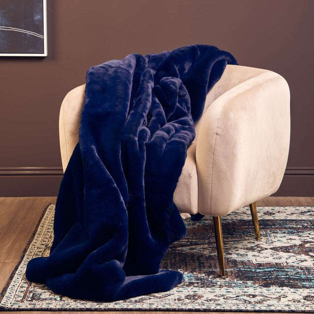 Orsina Navy Fur Throw draped over a cream armchair for a cozy living space