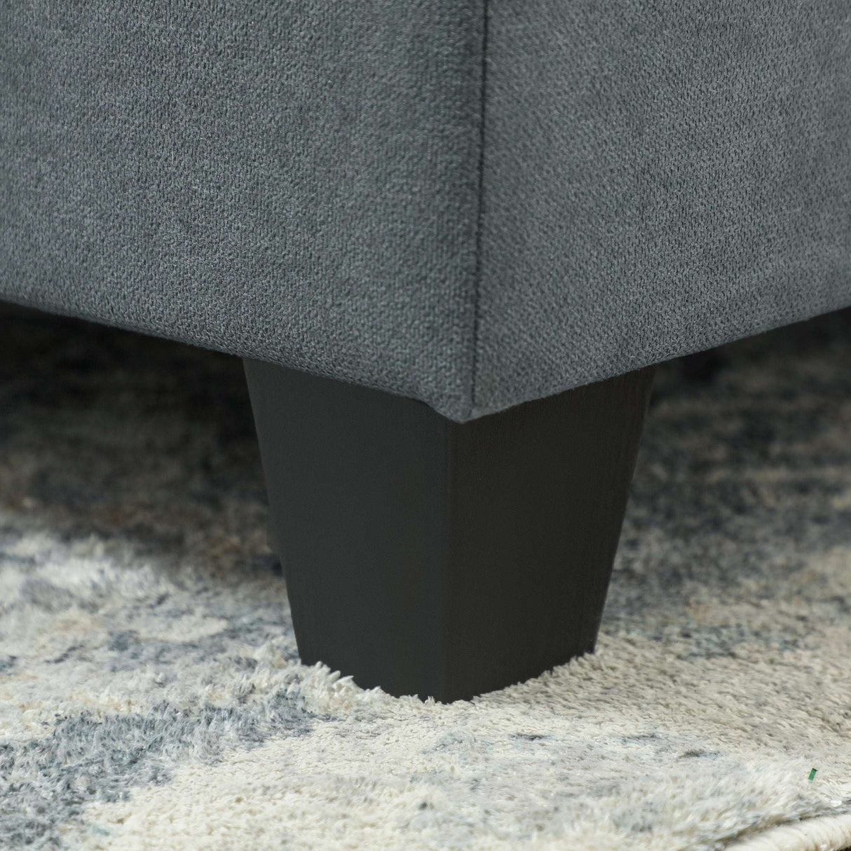 Close-up of a Wise Galleria Modular Sofa leg in black, showcasing a sleek design on a plush rug