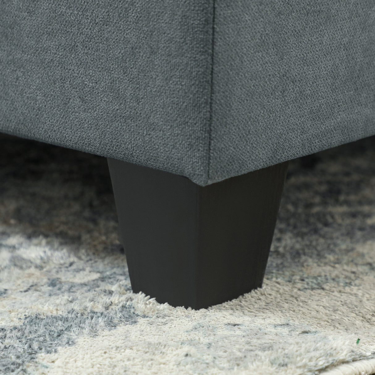 Close-up of a Wise Galleria Modular Sofa leg in black, showcasing a sleek design on a plush rug