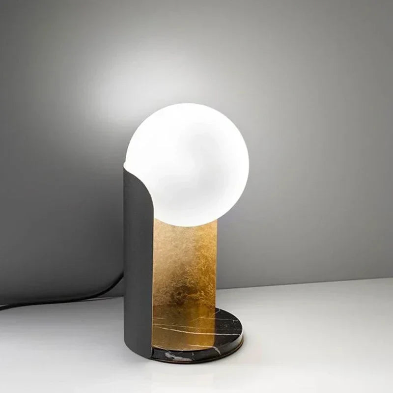 Norda Lamp from Nisu Home featuring a sleek design with a round glowing bulb and a gold accent base