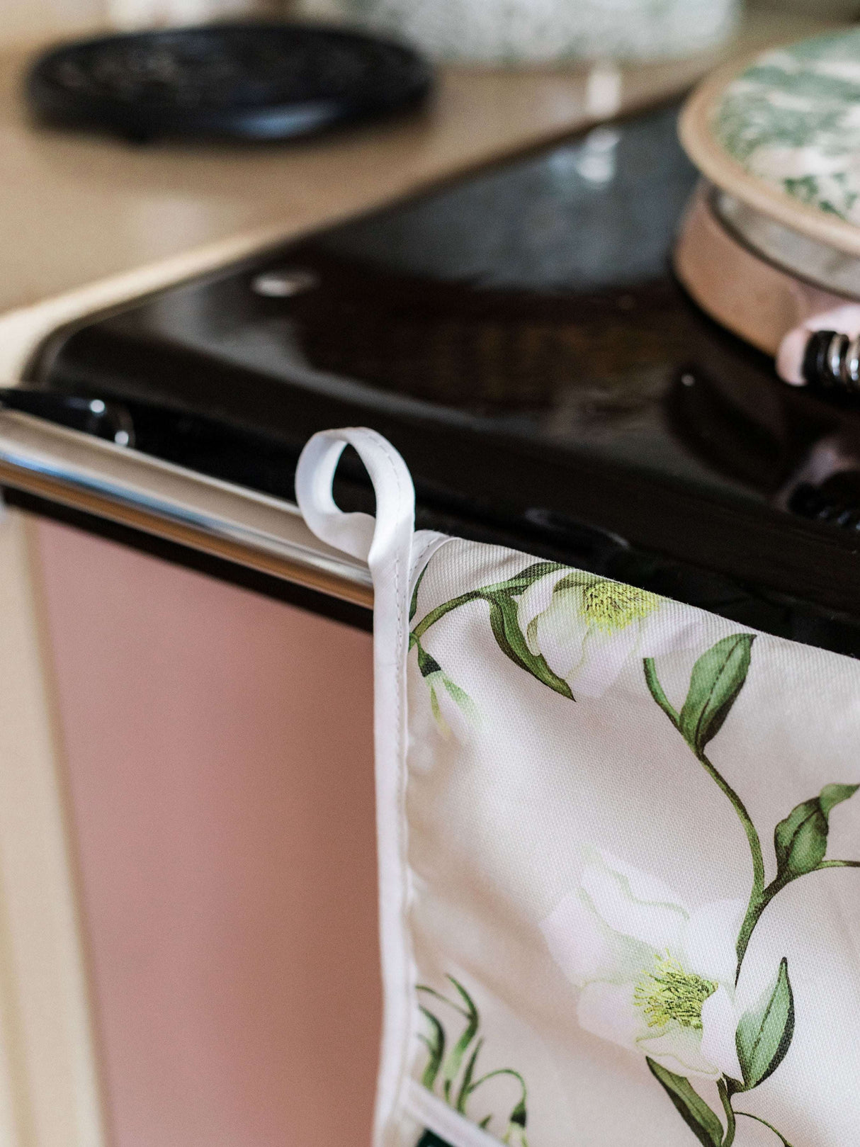 Stylish floral design oven glove hanging on a kitchen stove for safe cooking