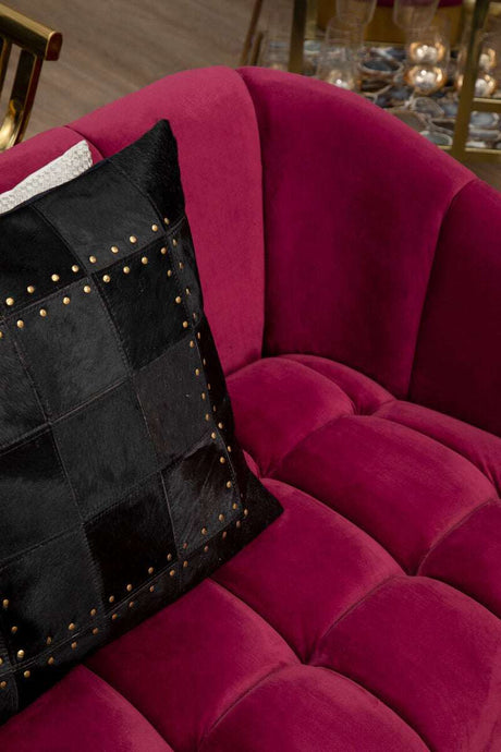Orsina Patchwork Cushion in Black with Decorative Studs on a Plush Pink Sofa
