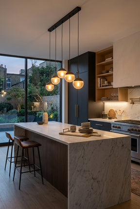 Orsina pendant light in a modern kitchen with five glowing orbs above a marble island