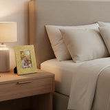 Orsina gold photo frame on bedside table next to lamp, displaying a family picture in a cozy bedroom