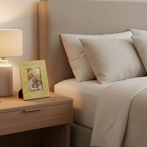 Orsina gold photo frame on bedside table next to lamp, displaying a family picture in a cozy bedroom