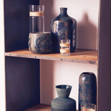 Orsina decorative planter in earthy tones displayed on a wooden shelf with glass vases