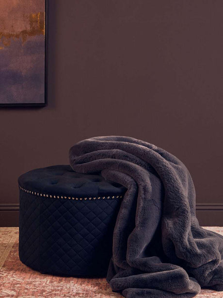 Orsina Fur Throw draped over a stylish ottoman in a modern room setting