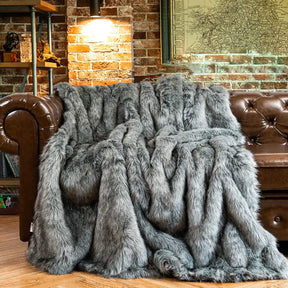Luxurious grey faux fur throw from Nisu Home draped over a leather sofa for added warmth and style