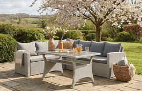 MINT Outdoor Rattan Corner Set with Grey Cushions in a Garden Setting under Cherry Blossom Trees