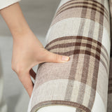 Close-up of a hand on a stylish Reclining Armchair with a brown plaid design for comfort and relaxation