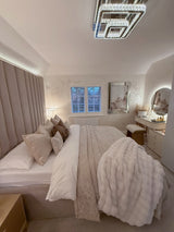 Elegant round mirror above a stylish vanity in a modern, plush bedroom setting with soft bedding and decor
