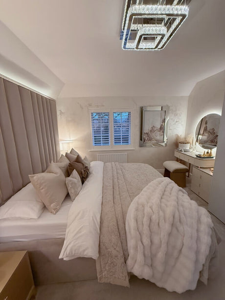 Elegant round mirror above a stylish vanity in a modern, plush bedroom setting with soft bedding and decor