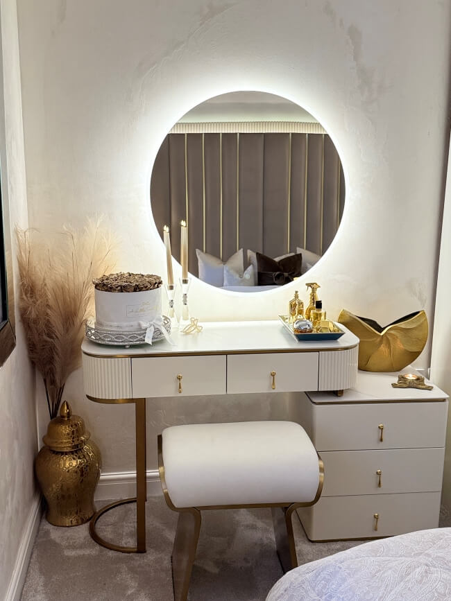 Elegant round mirror with LED lights above a stylish vanity table in a chic bedroom setting