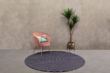 Orsina Round Rug in navy blue with geometric pattern, complementing a stylish pink chair and indoor plant