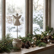 Rustic Angel Decoration in a Pot on a Frosted Window Sill with Pinecones and Fairy Lights
